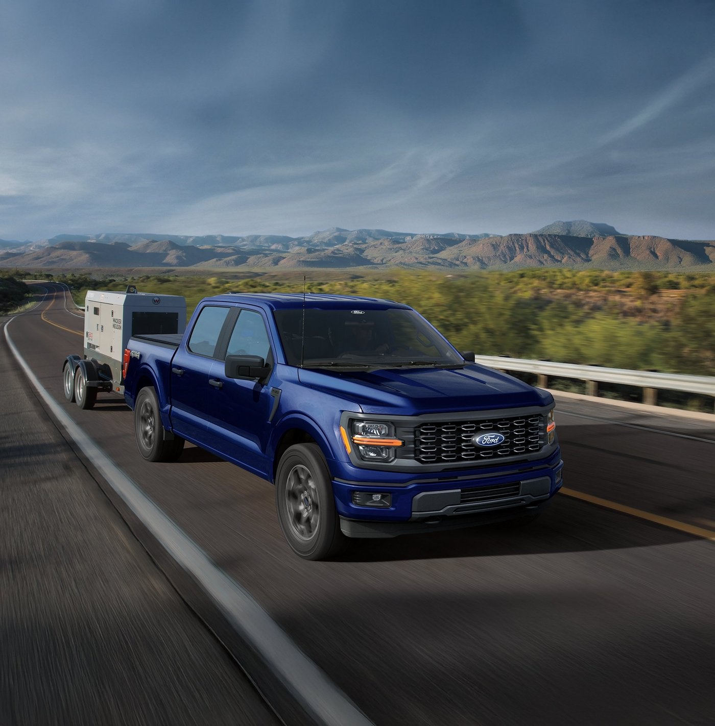 Blue Ford F-150 towing a small enclosed trailer on a two lane highway Blue Ford F-150 towing a small enclosed trailer on a two lane highway, half ton towing for Farmington MO