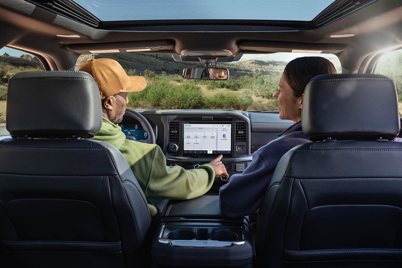 Couple in a Ford F-150 using the center touchscreen with a panoramic roof overhead, Farmington MO