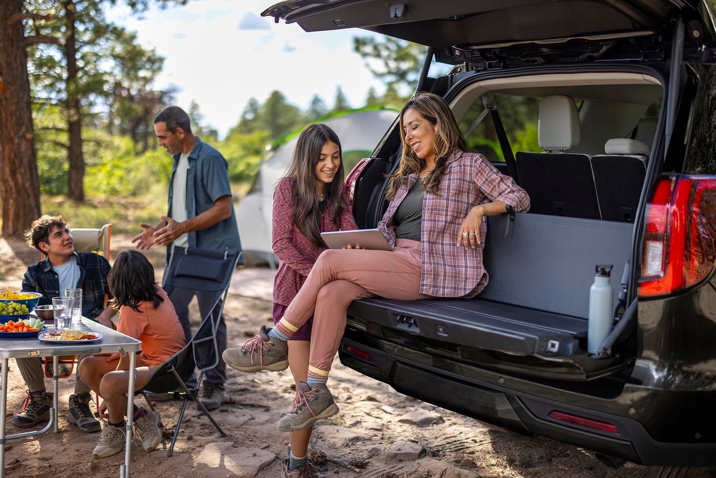 Family camping beside a black Ford Expedition, mother and daughter sitting in the open cargo area, Farmington MO