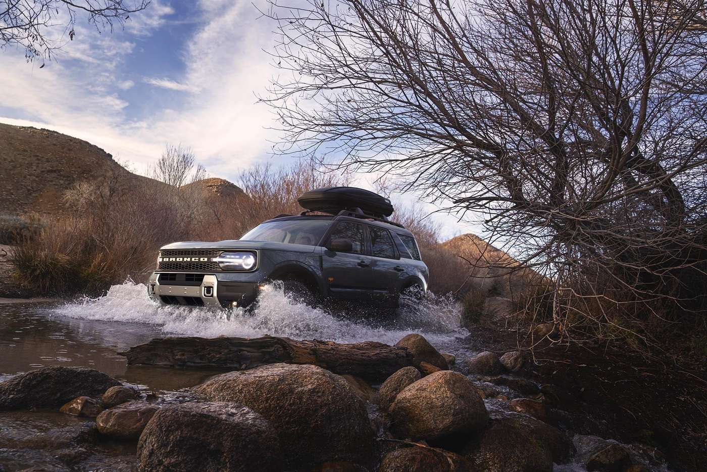 Ford Bronco Sport with a roof box crossing a rocky creek, water splashing, Farmington MO