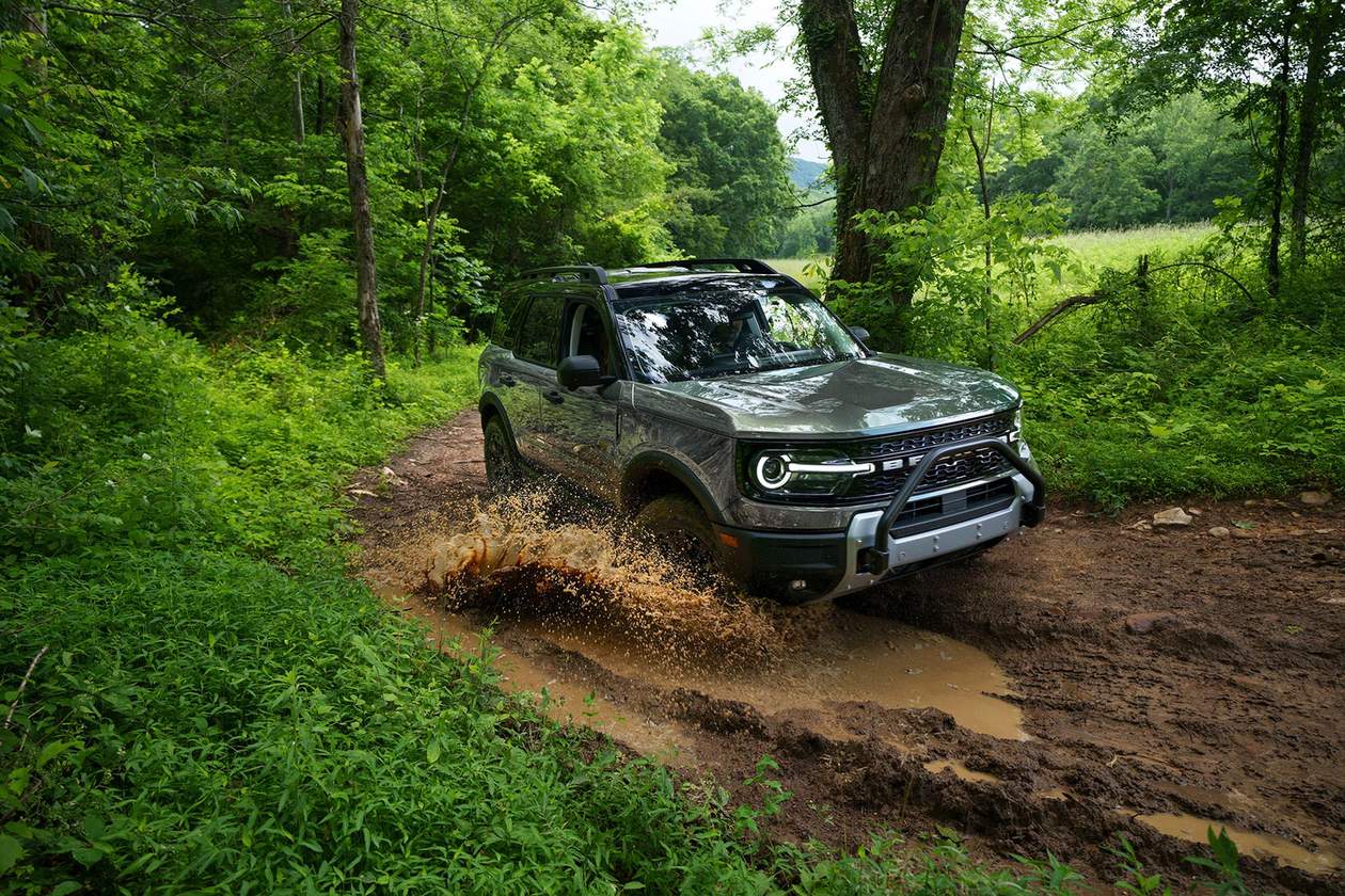 Green 2026 Ford Bronco Sport with a brush guard splashing through a muddy wooded trail, Farmington MO