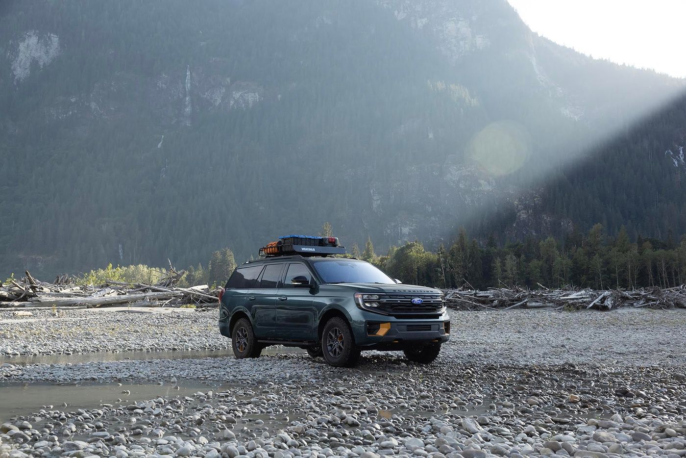 Dark green Ford Expedition Tremor with a roof rack parked on a gravel riverbed below mountains, Farmington MO