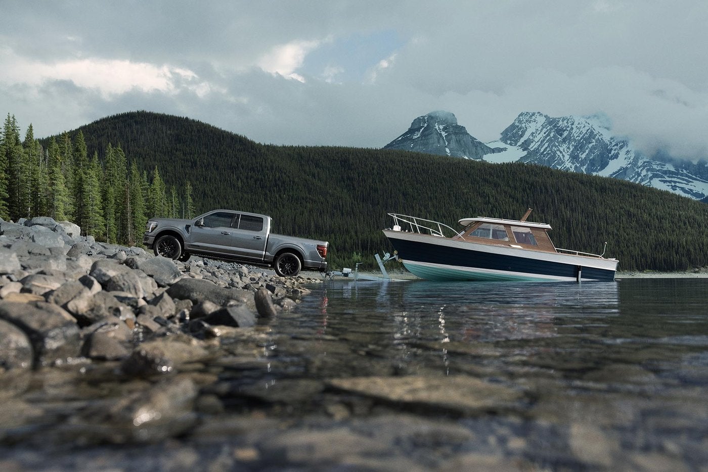 Gray Ford F-150 backing a boat into a mountain lake, summer towing that works the cooling system, Farmington MO