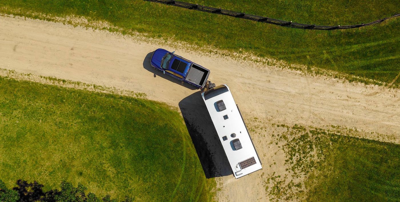 Overhead view of a blue Ford F-150 backing a camper trailer down a gravel lane Overhead view of a blue Ford F-150 backing a camper trailer down a gravel lane, towing help for Farmington MO