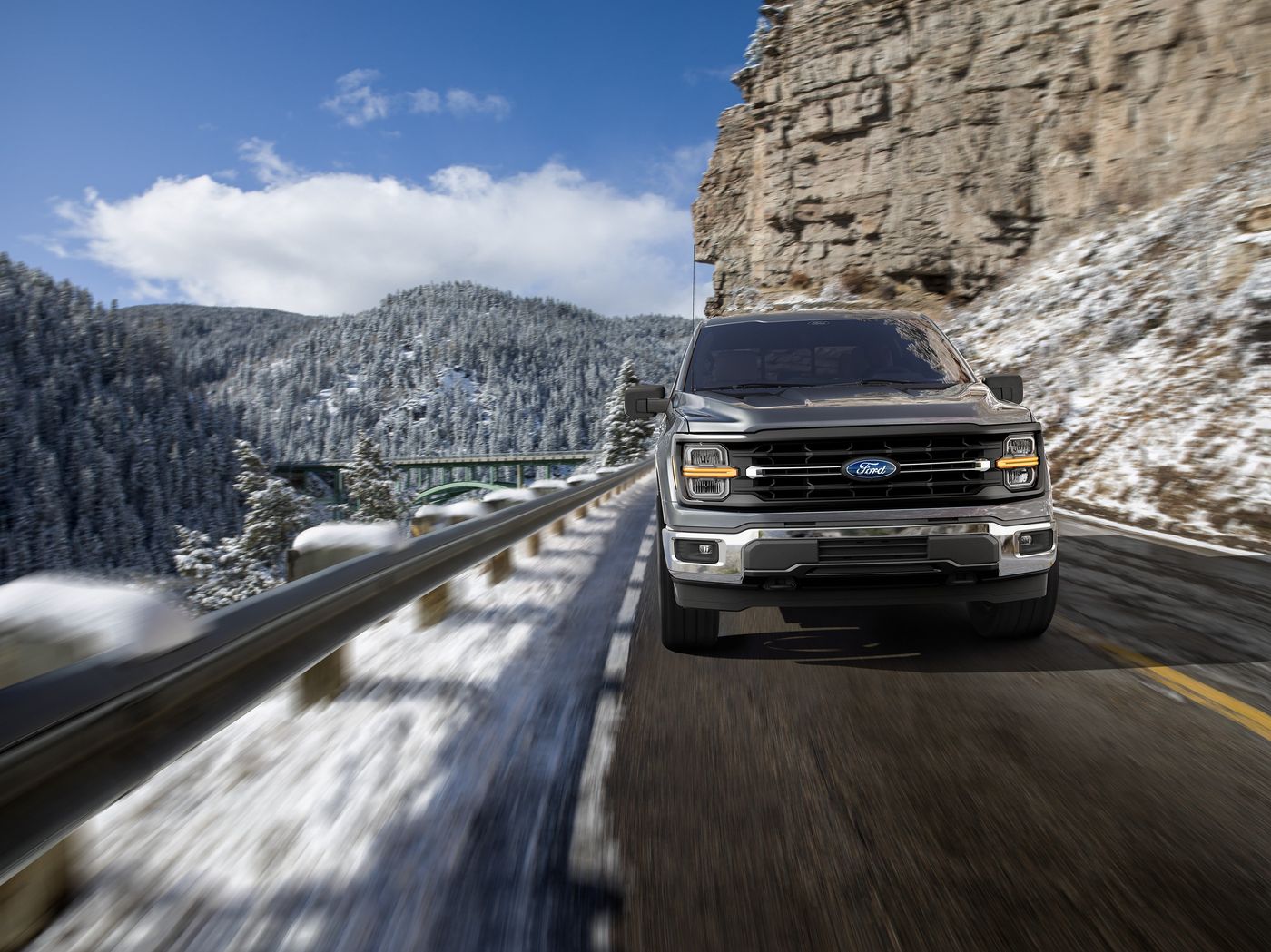 Gray Ford F-150 Lariat driving a snowy mountain highway, winter oil change timing for Farmington MO drivers