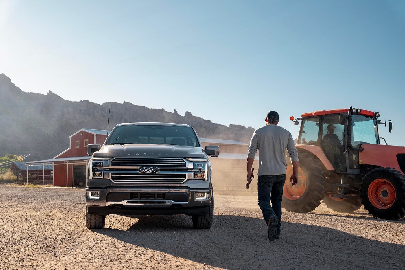 Gray Ford F-150 Platinum parked at a farm as a man walks toward a red tractor, F-150 trims in Farmington MO