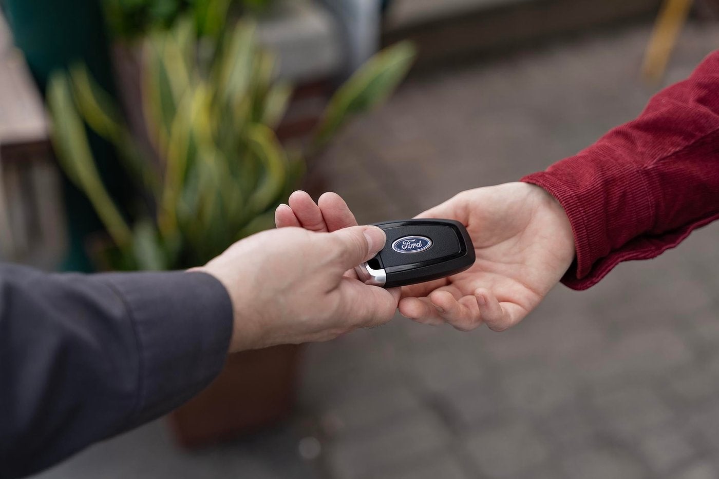 Close up of a Ford key fob passing from one hand to another, selling your car in Farmington MO