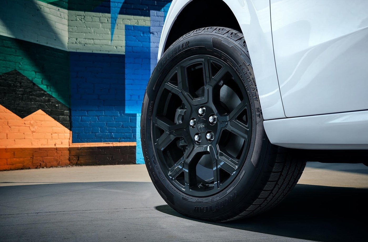 Close up of a gloss black Ford Maverick wheel and tire on a white truck, tread check before winter in Farmington MO