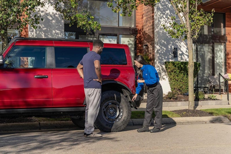 Ford service rep going over results with a Bronco owner at the curb