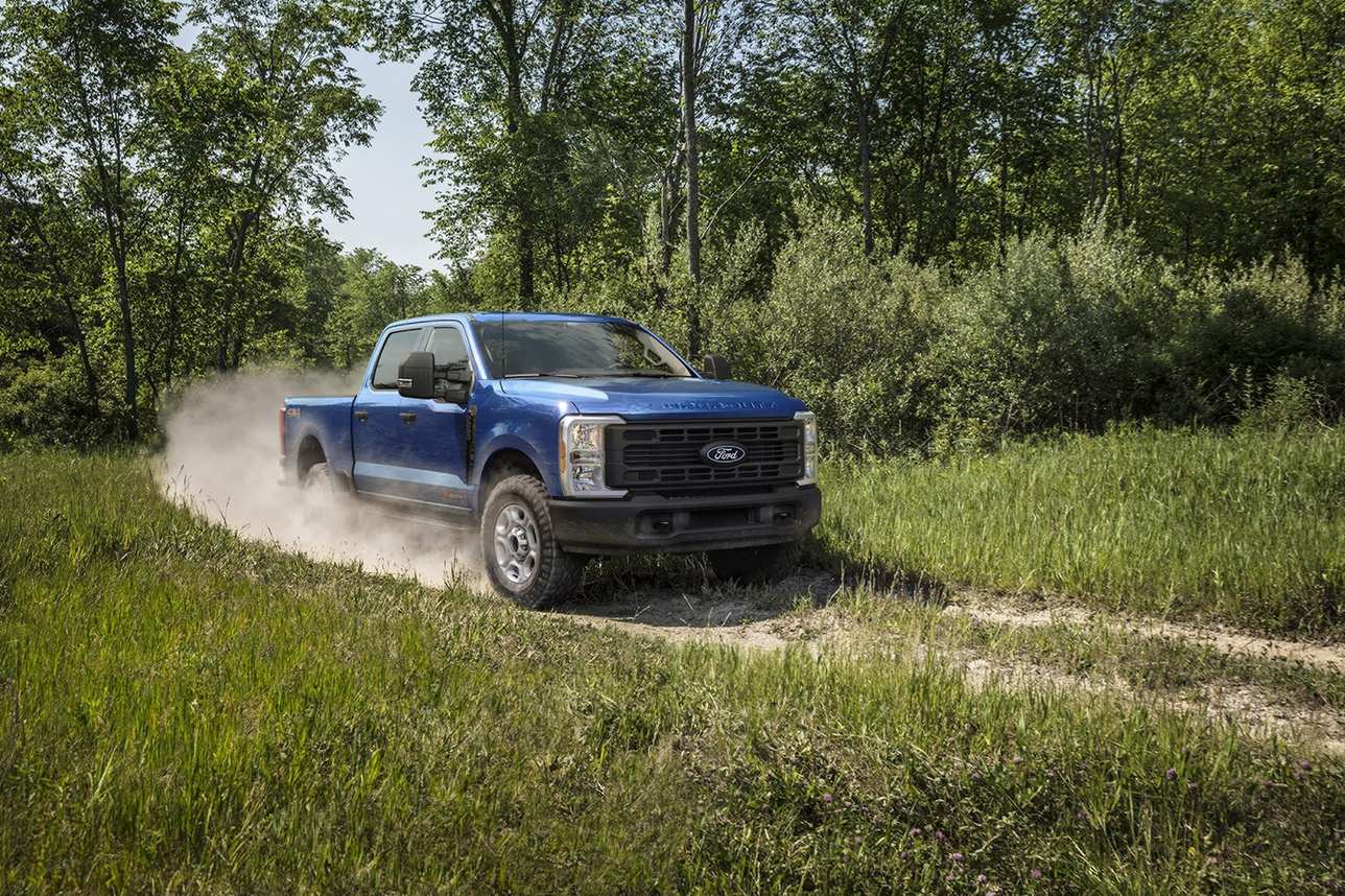 Blue Ford Super Duty F-250 XL kicking up dust on a grassy two track path, farm truck work near Farmington MO