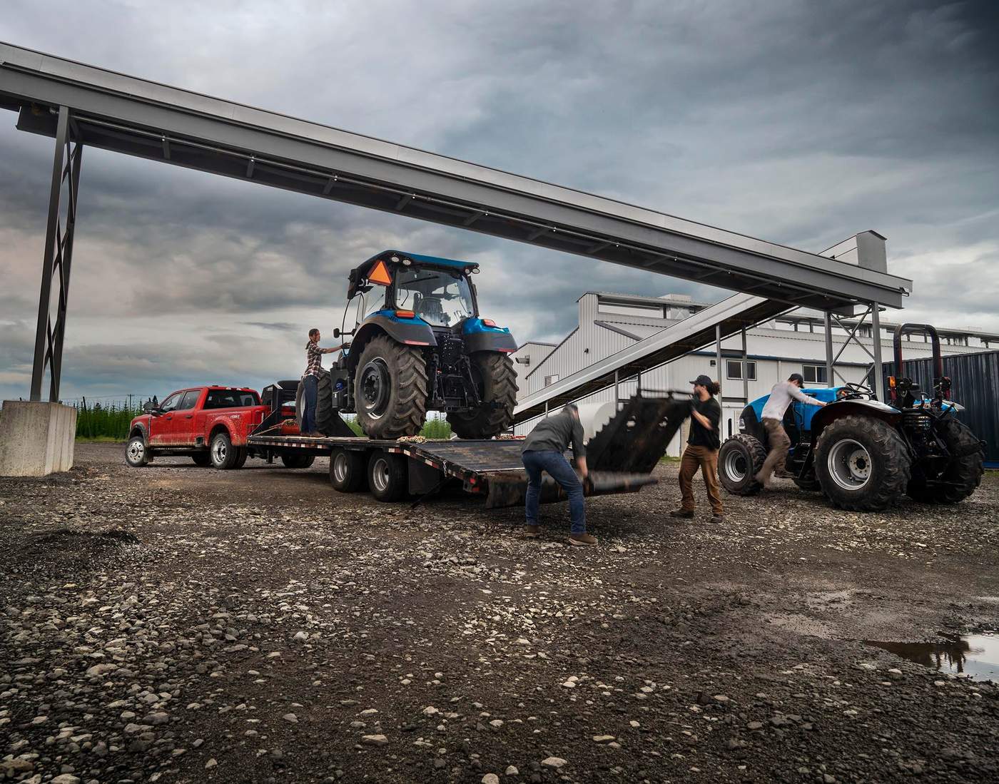 Red Ford Super Duty F-450 hitched to a flatbed as a crew unloads tractors, diesel towing work in Southeast Missouri