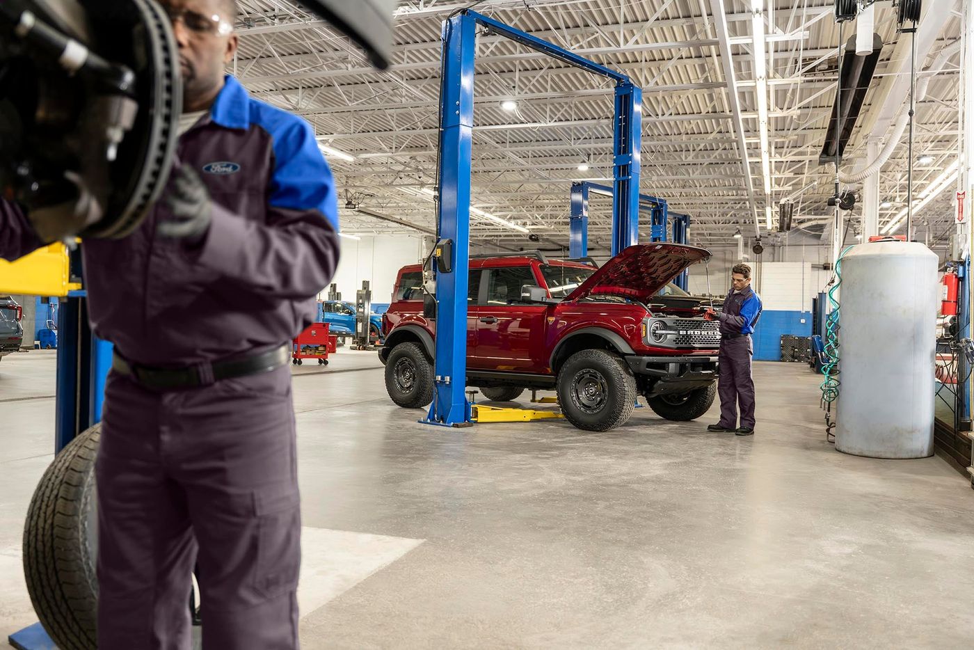 Ford technician holding a brake rotor and hub in the service bay Ford technician holding a brake rotor and hub in the service bay, part of hybrid brake checks in Farmington MO