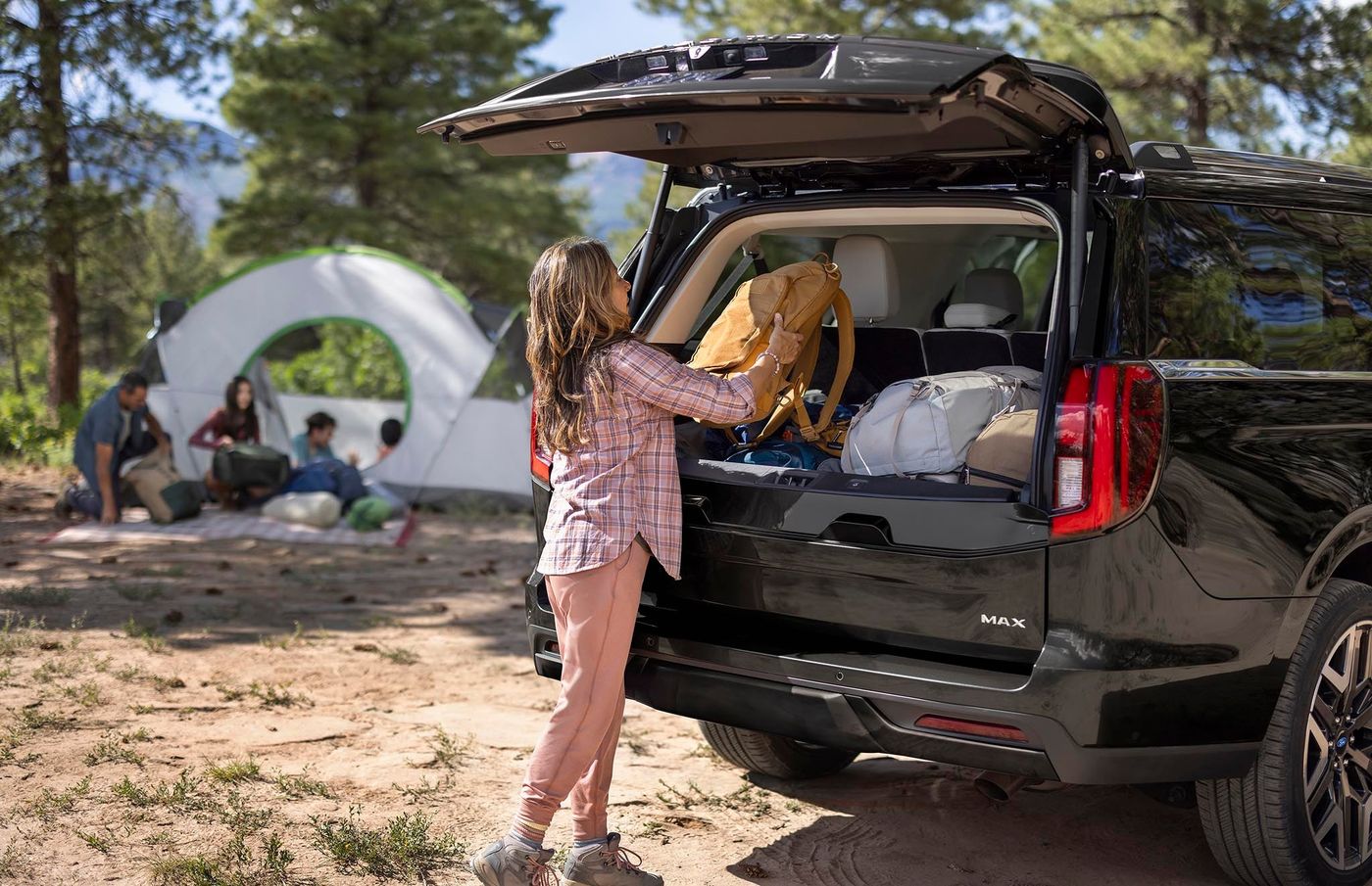 Girl loading a bag into a black Ford Expedition with the rear gate open at a family campsite Girl loading a bag into a black Ford Expedition with the rear gate open at a family campsite, Farmington MO