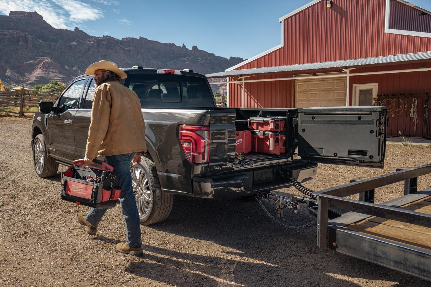 Man carrying a tool bag to a Ford F-150 with the Pro Access Tailgate open beside a red barn, Farmington MO