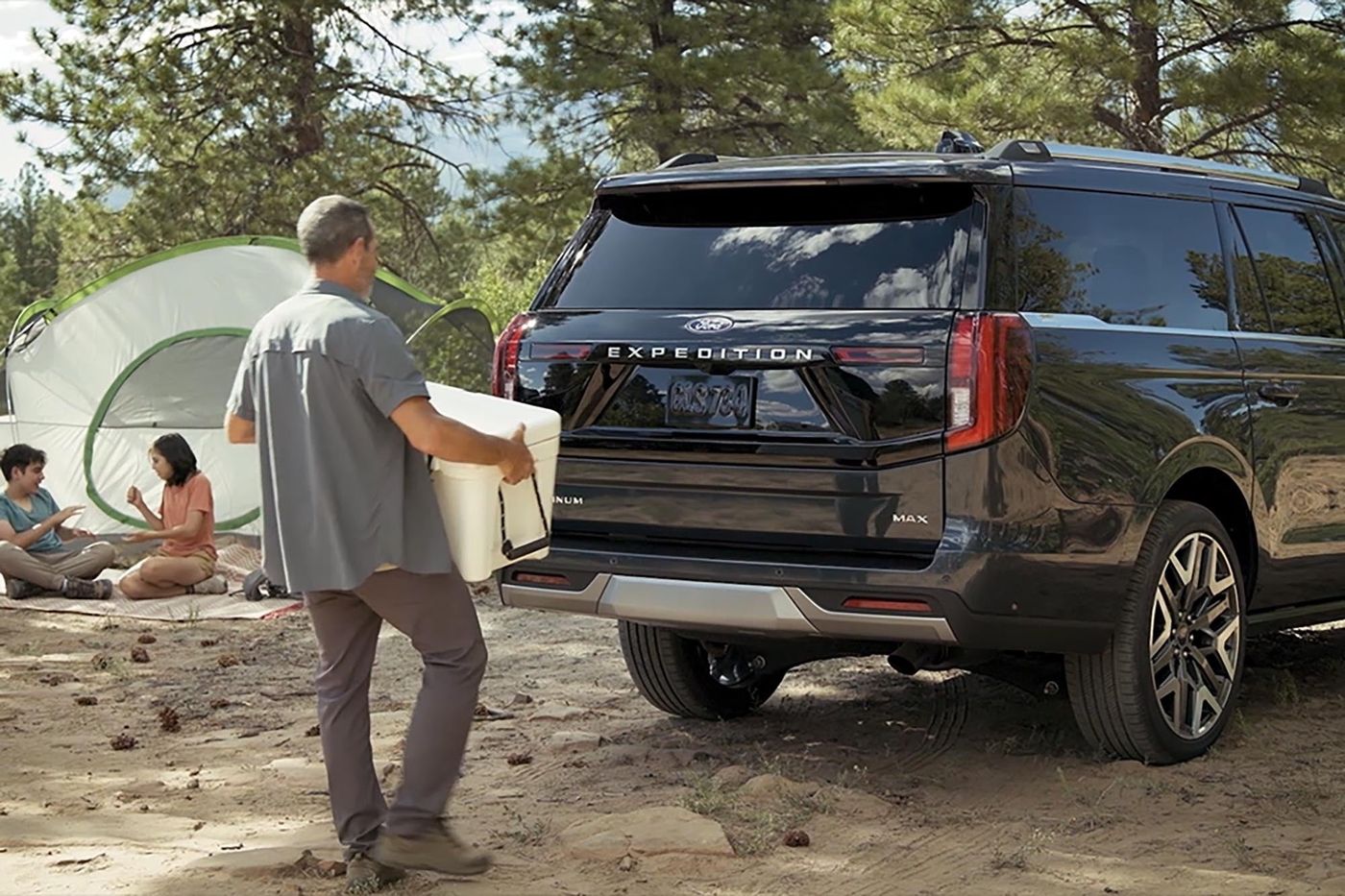 Man loading a cooler into a black Ford Expedition MAX at a family campsite, rear gate open, Farmington MO