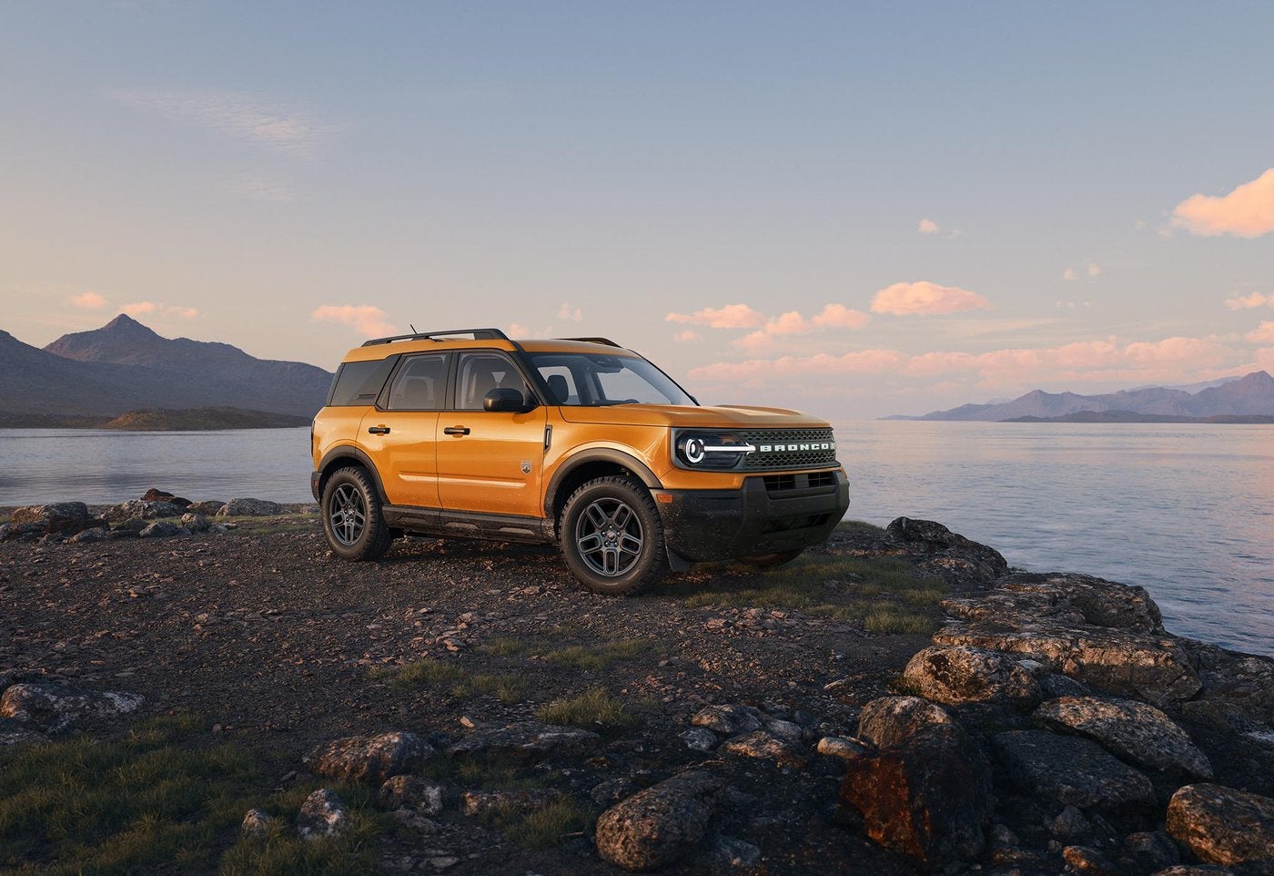 Orange Ford Bronco Sport parked on lakeside rocks at sunset, Ozark weekend ideas from Farmington MO
