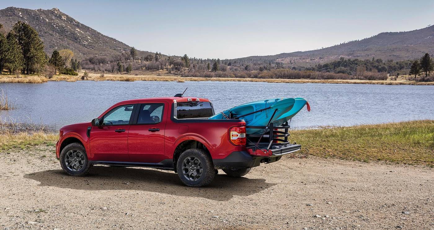 Red Ford Maverick parked by a lake with two kayaks in the bed Red Ford Maverick parked by a lake with two kayaks in the bed, weekend hauling for Farmington MO owners