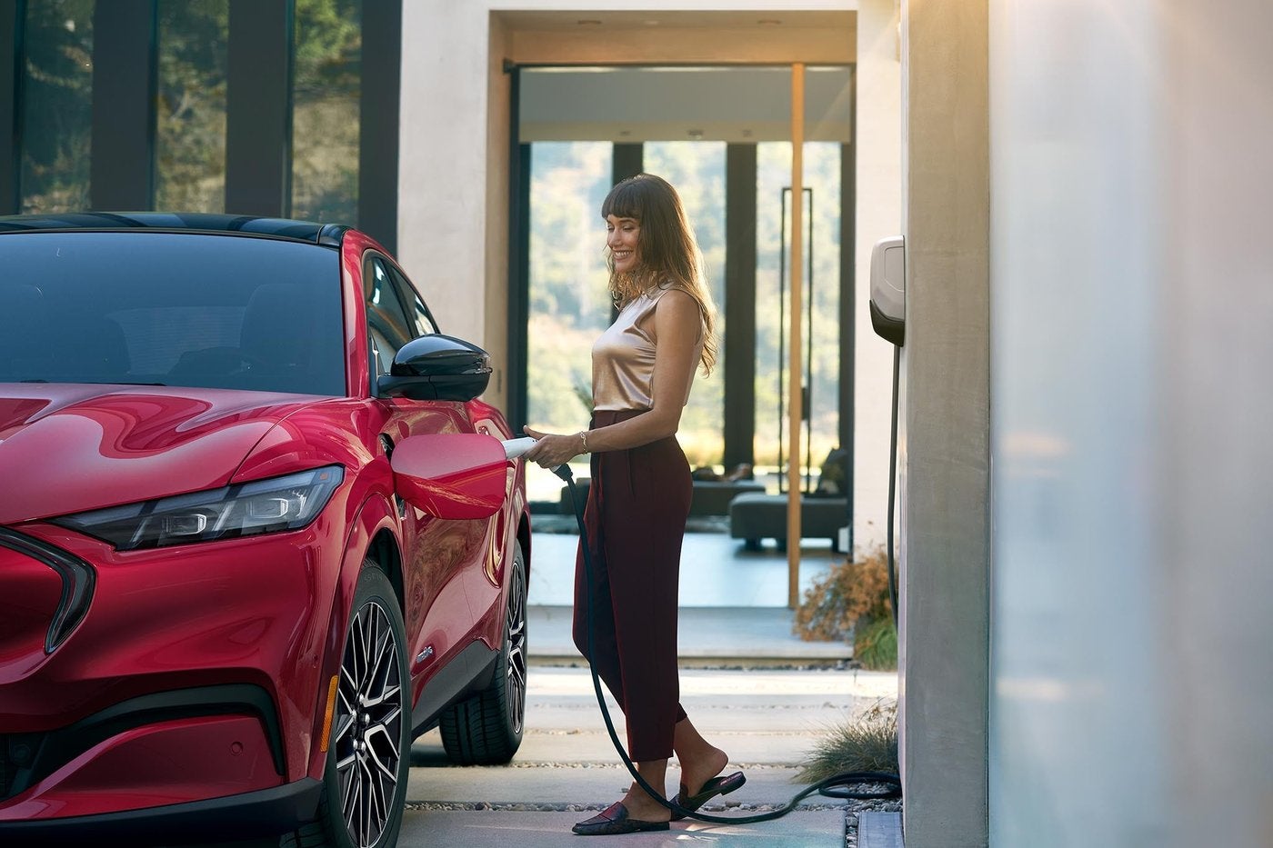 Woman plugging a home charger into a red Ford Mustang Mach-E, home charging basics for Farmington MO
